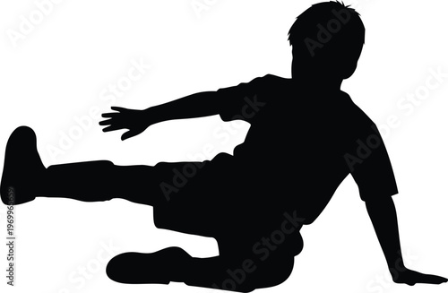 Silhouette of a young boy in motion playing soccer and kicking a ball during a match or training session