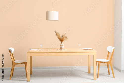 Vase of pampas grass on  served dining table and chairs in light room