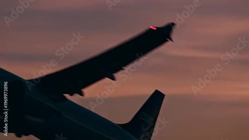 Airplane silhouette against vibrant sunset sky, dramatic orange clouds, travel concept