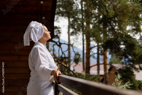 a woman in a white robe and a towel on her head, with mountains in the background, in a hotel