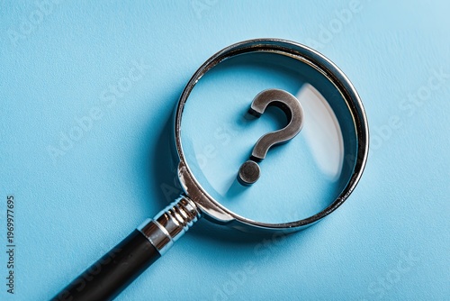 Magnifying glass enlarging a silver question mark on a bright blue surface