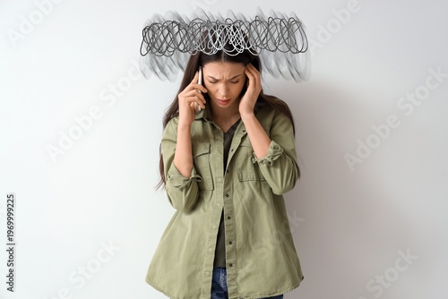 Fotografie Portrait of worried young woman talking by phone on grey background