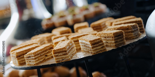 A close-up of layered pastries and canapes arranged on a tiered tray at a buffet, showcasing a variety of sweet treats in a sophisticated setting.