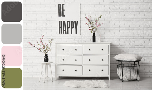 Dresser with coffee table, different decor and vases of blooming branches near white brick wall in living room