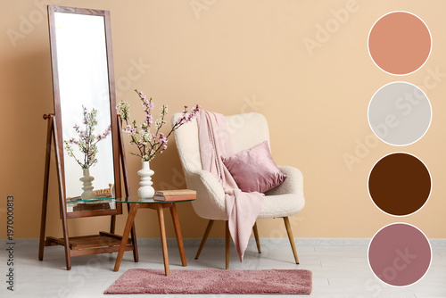 Armchair with mirror, coffee table and vase of blooming branches near beige wall in living room