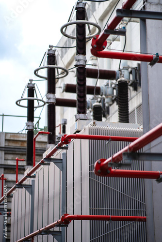 Принти на полотні Close-up of power transformers with red fire protection piping and high voltage bushings, showing cooling structures, safety systems, and substation infrastructure outdoors