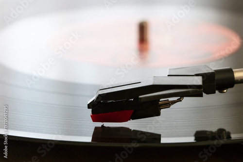detail of a turntable with cartridge and 33 rpm vinyl record in the foreground
