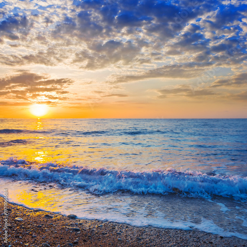 calm sea bay with sandy beach at the sunrise under a cloudy sky