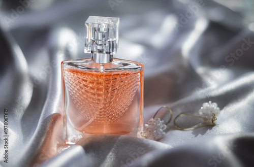 Luxury women’s perfume with elegant earrings on silk background, premium beauty and fashion concept