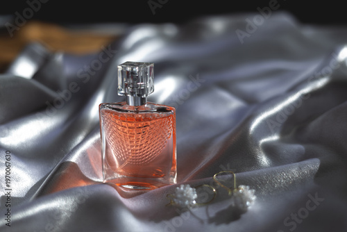 Luxury women’s perfume with elegant earrings on silk background, premium beauty and fashion concept