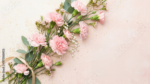 Soft pink carnations and eucalyptus arranged elegantly with a golden ribbon accent
