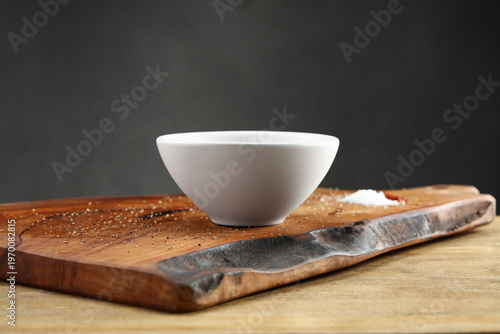 White bowl on wooden cutting board with spices. Selective focus