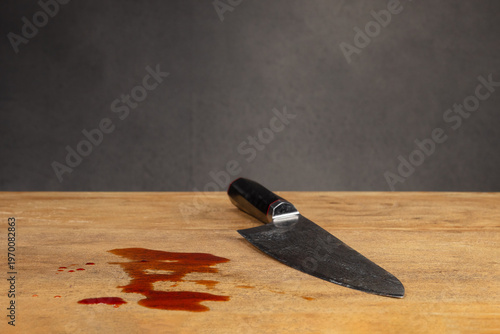 Knife on the table with blood. Blood and knife on the big wooden cutting board. Selective focus on a drop of  blood
