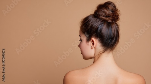 Young woman with hair bun from behind bare shoulders beauty skincare portrait