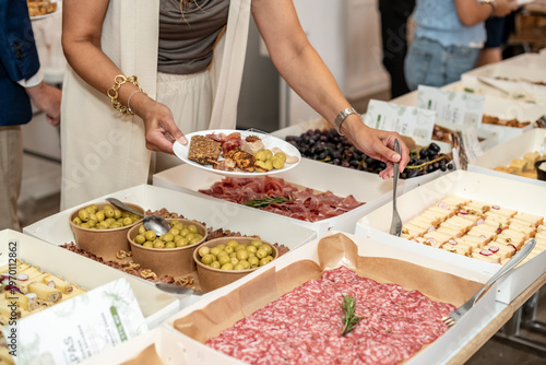 Woman Serving Herself at a Gourmet Tapas Buffet during a Social Event
