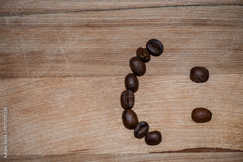Smiley face made of coffee beans on wooden table
