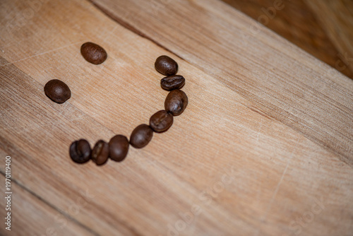 Smiley face made of coffee beans on wooden table