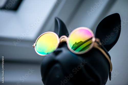 Stylish black dog figurine wearing round mirrored sunglasses