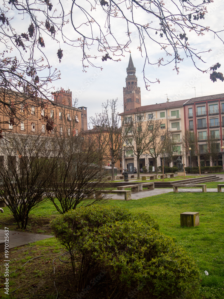 Obraz premium Piazza Marconi in Cremona presenting the Torrazzo bell tower and Stradivarius statue within the city square park green space
