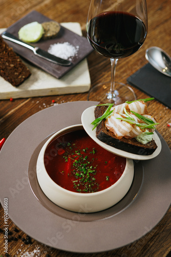 A vibrant Red Soup with fresh Bread and elegant garnish on a rustic Wooden Table