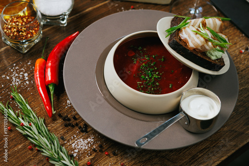A vibrant Red Soup with fresh Bread and elegant garnish on a rustic Wooden Table