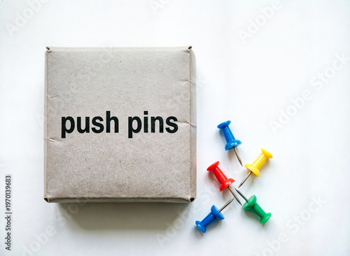 cardboard box and few loose push pins on white
