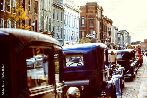 Rear view of antique cars parked in a row along an old town sidewalk