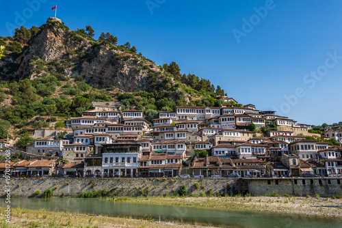 Bild auf Leinwand A classic wide view of Berat's renowned Mangalem district, where white Ottoman houses ascend a verdant hill, crowned by Berat Castle, visible across the Osum River in Berat, Albania