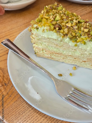 Pistachio napoleon cake slice with cream layers on plate