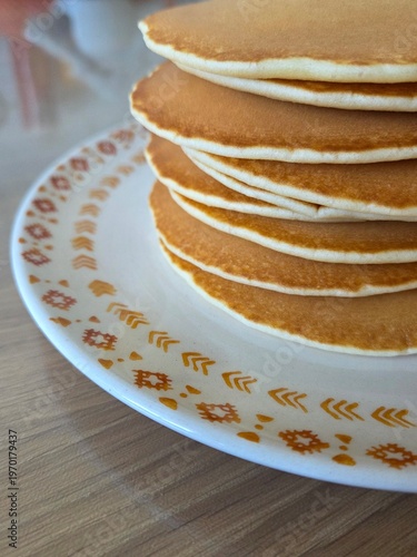 Homemade pancakes stacked on plate on wooden table