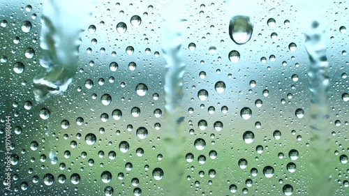 A close-up view of water droplets on a surface with reflections. Captured in natural light, showcasing various droplet sizes