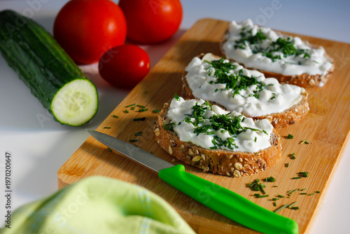 Whole grain bread slices with cottage cheese and fresh chives on wooden board, healthy breakfast or snack with vegetables, rustic homemade food concept, natural light food photography with copy space