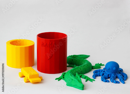 Colorful 3d printed objects including cups, toy car, dragon and octopus on white background, modern additive manufacturing concept, creative hobby and technology, plastic models with copy space
