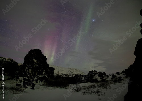 Red and green aurora borealis through the clouds in Thingvellir Iceland