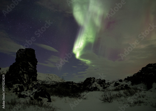 Strong aurora borealis through the clouds in Thingvellir Iceland