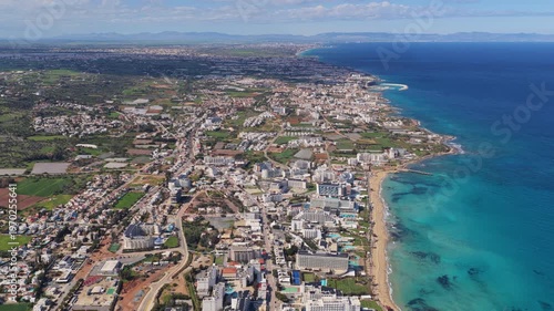 Aerial drone view of Protaras and Paralimni coastline, Cyprus, showing long sandy beaches, turquoise sea, and dense urban development stretching along the Mediterranean shore
