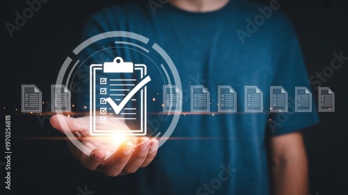 A person holds a glowing checklist icon with documents floating around on a dark background with blue t shirt