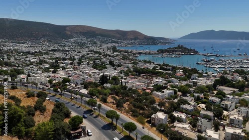 Aerial drone view of Bodrum city in Turkey with marina, yachts and white houses. Scenic Mediterranean coastline with mountains and blue sea in summer.