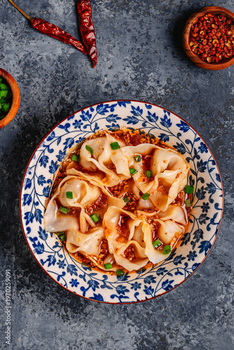 Wontons are placed in a bowl with spicy sauce.