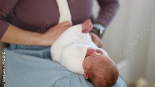 Mom Gently Wraps Newborn In Soft Wrap In Comfortable Setting While Baby Small Hand Reaches Out.