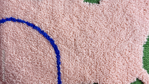 plush pink tufted rug closeup reveals soft fluffy texture and bold blue curved design with green tufts