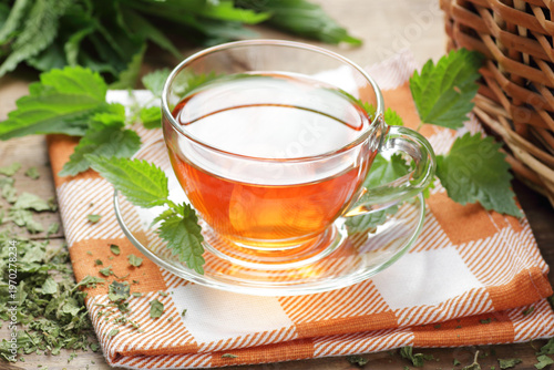 Nettle leaf tea with fresh green leaves on wooden rustic table, closeup, copy space, natural medicine, diet food and drink, homeoparhy, hair and skin healthy care, detox and diet healthy food concept