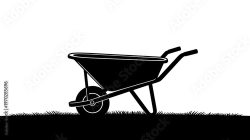 Black silhouette of a wheelbarrow on grassy ground  