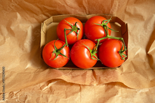 Clean aesthetic shot of five ripe tomatoes on vine in an eco-friendly box, emphasizing healthy lifestyle and clean eating.