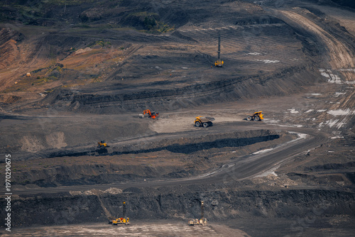 Fotografie Expansive open pit mine with heavy machinery extracting resources, excavator loa