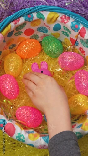 Vertical Shot Of A Kid's Hand Putting A Plastic Easter Bunny In A Basket