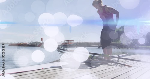 Rower checking rigging on dock, boarding scull for rowing while bokeh overlay drifting over rower