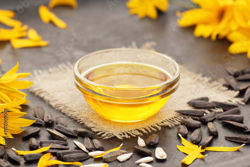 Sunflower oil with fresh flowers, seeds, petals on black table, closeup, copy space, cooking ingredient, face skin and hair care, natural organic food concept