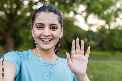 Smiling young woman waving hello during outdoor fitness exercise