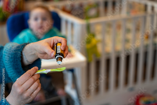 Baby vitamin D supplementation with liquid drops on spoon given by parent